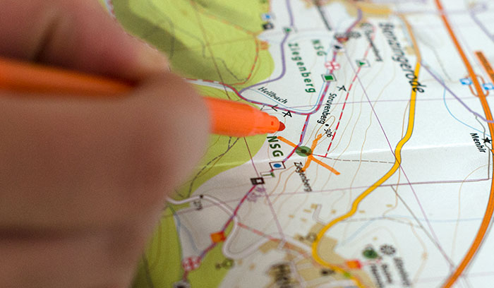 Mit einem Stift wird eine Stempelstelle auf einer Wanderkarte durchgestrichen.