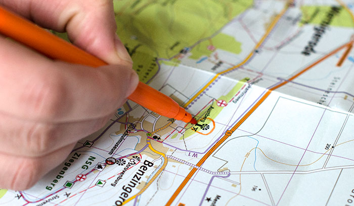 Mit einem Stift wird eine Stempelstelle auf einer Wanderkarte durchgestrichen.