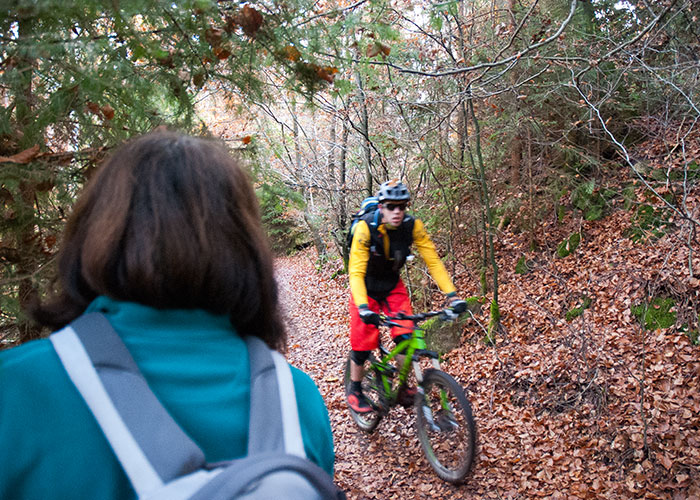 Ein Mountainbiker fährt an einer Wanderin vorbei